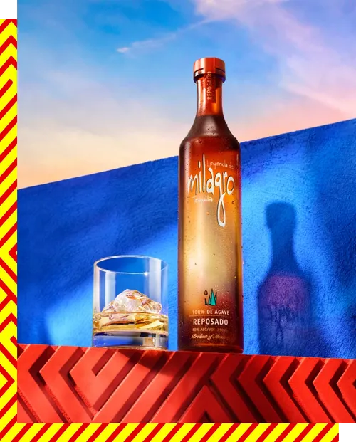 A bottle of Milagro Reposado tequila with a glass