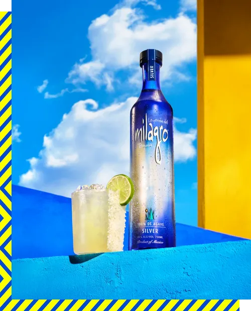 A bottle of Milagro Silver tequila with a glass